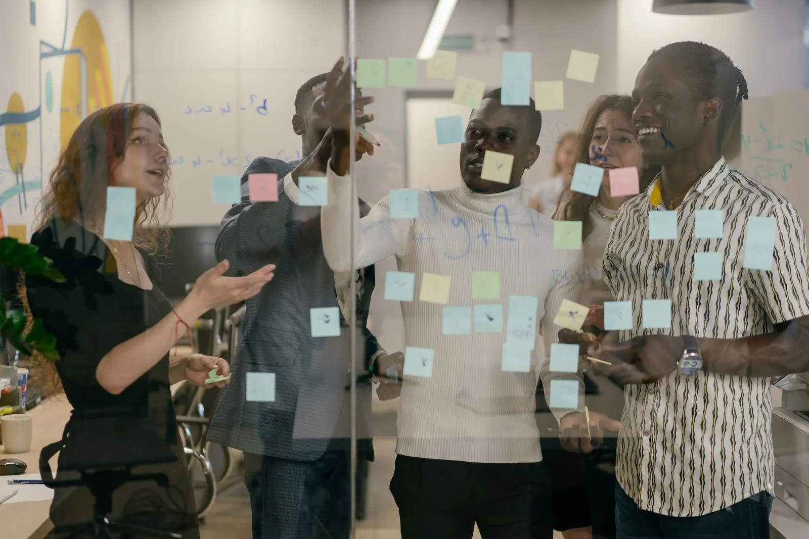 Une équipe en atelier, réunie autour d'une paroi de notes adhésives